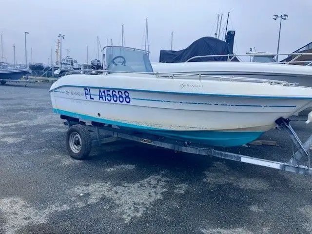 Jeanneau Cap Camarat 475 — Bateau à moteur blanc sur remorque, photographié de profil dans un port.