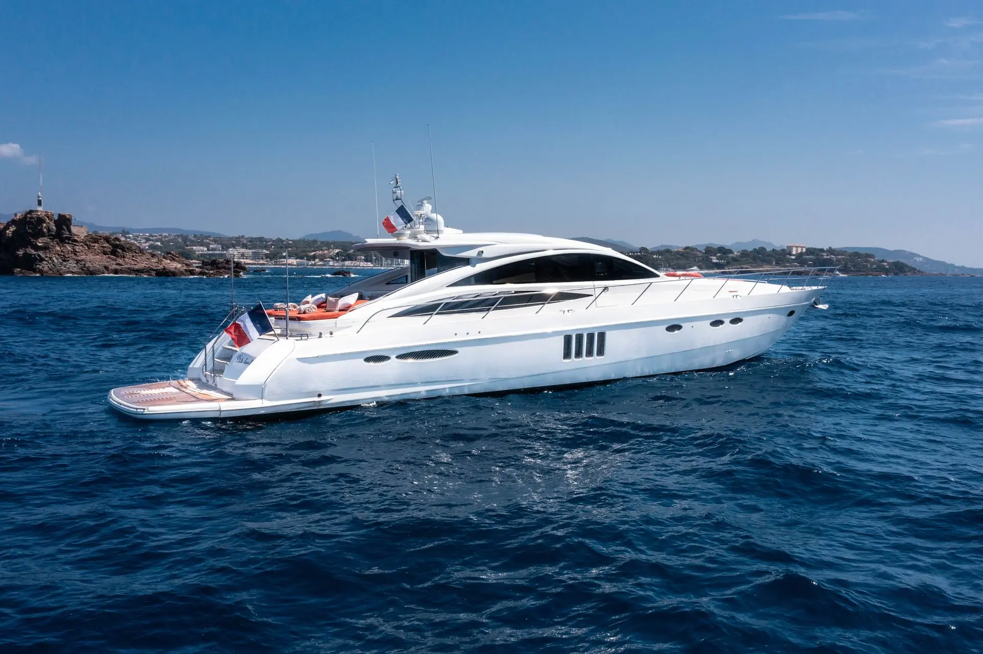 Princess V70 — Bateau à moteur blanc vu de trois quarts sur une mer bleue, près de la côte.