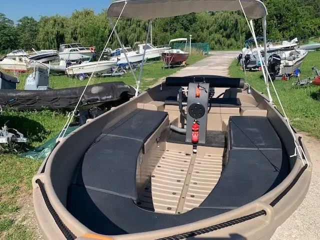 Whaly 450 — Bateau ouvert à console centrale, sièges latéraux et taud sur un terrain nautique.