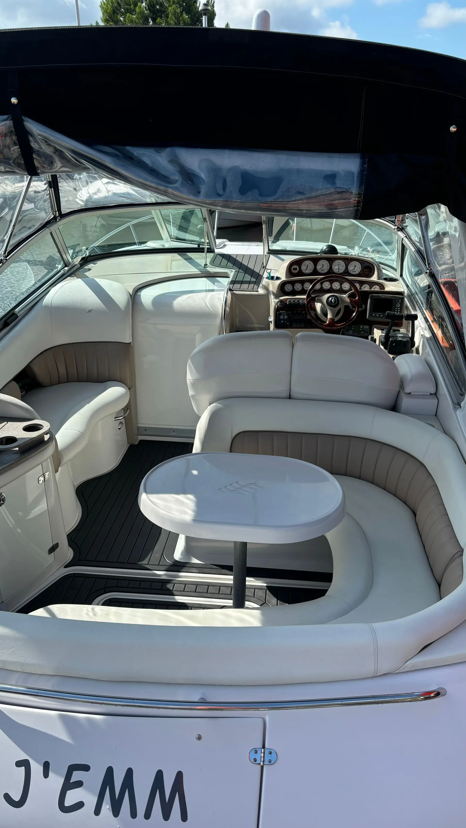 Four Winns Vista 288 — Cockpit avec sièges, table, poste de pilotage et taud de protection.