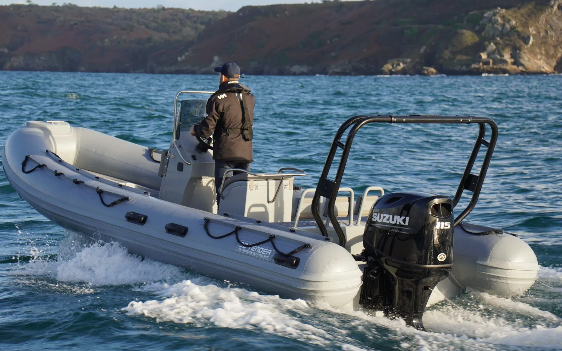 3D Tender XPRO 589 — Bateau semi-rigide en navigation près d'une côte rocheuse, avec un pilote à bord.