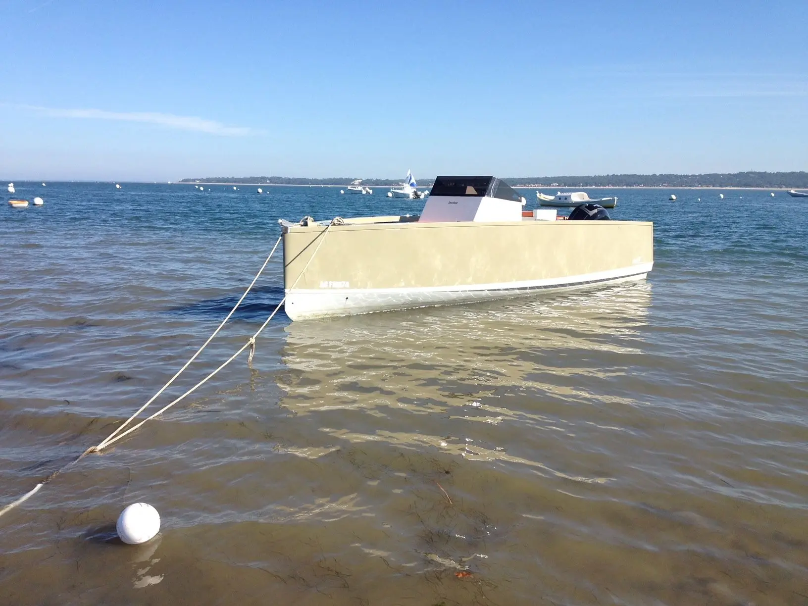 Smartboat 23 — Bateau à moteur vu de trois quarts, amarré dans une baie par temps ensoleillé.