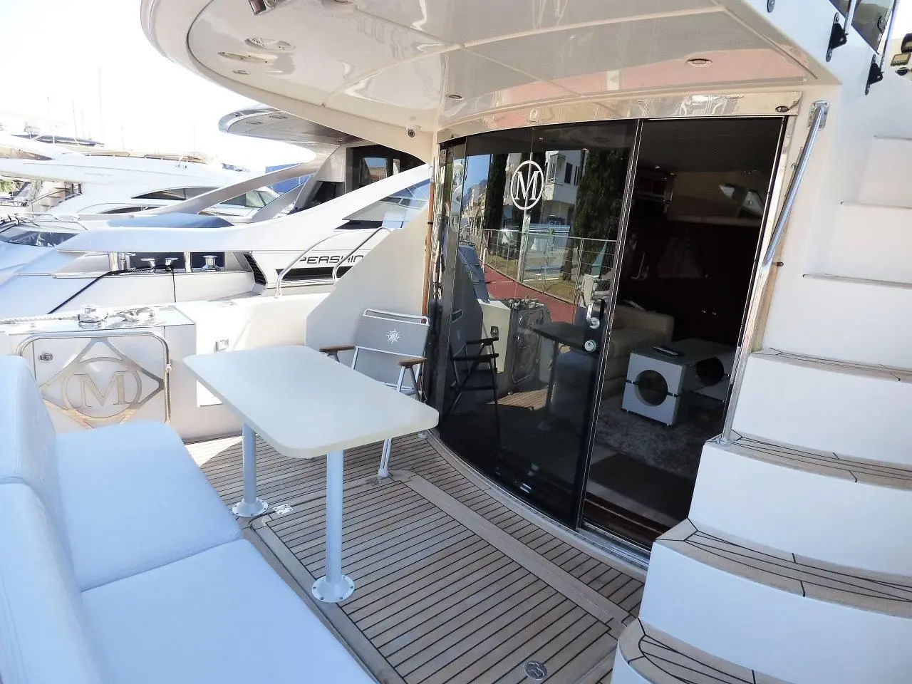 Marquis Yachts 560 — Cockpit arrière avec table, banquette et accès intérieur vitré.