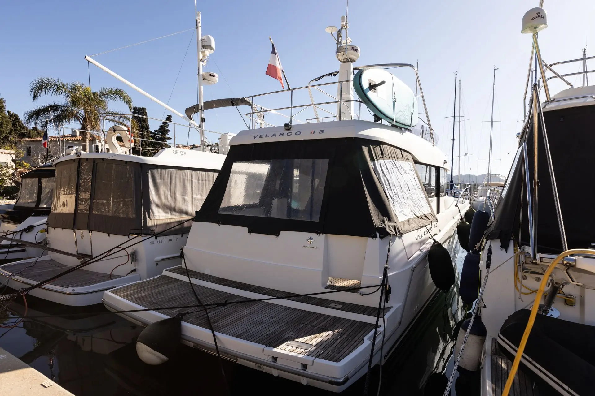 Jeanneau Velasco 43 F — Bateau à moteur blanc vu de trois-quarts arrière dans un port.