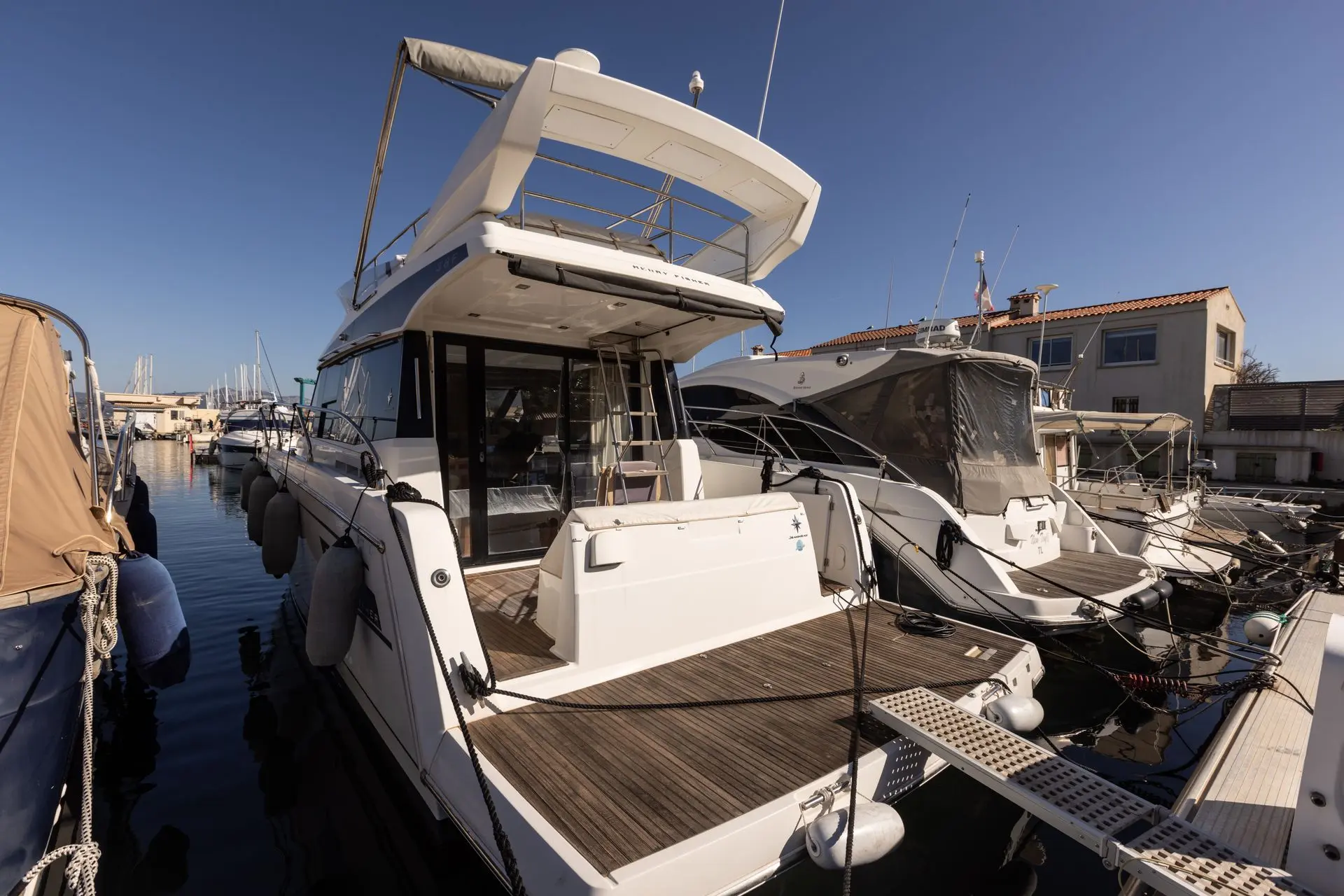 Jeanneau Merry Fisher 38 Fly — Vue arrière d’un bateau à moteur amarré dans un port.