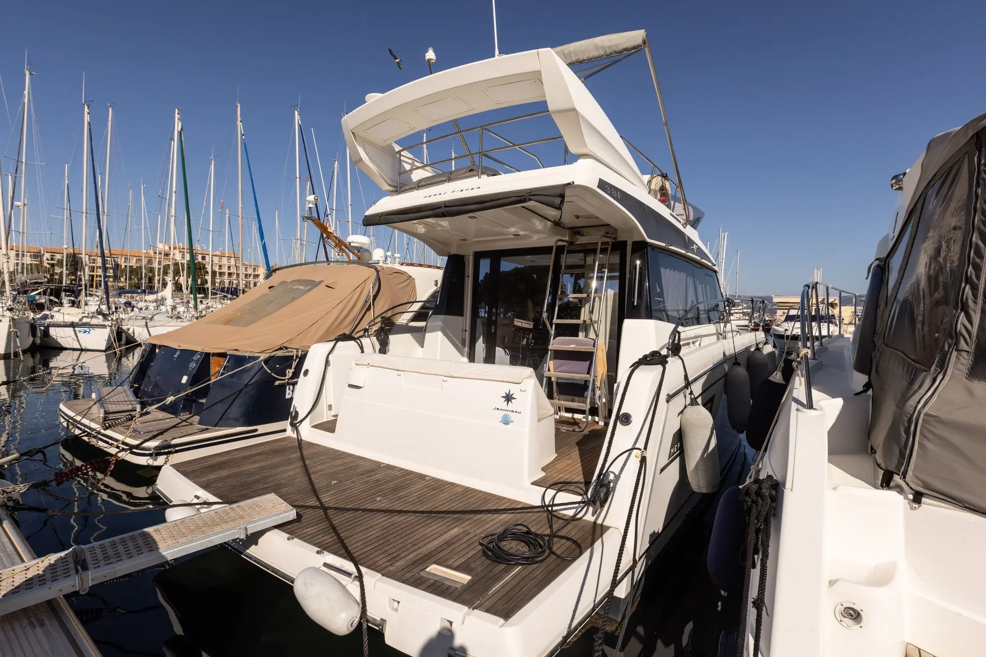 Jeanneau Merry Fisher 38 Fly — Bateau à moteur blanc amarré dans un port, vu depuis l’arrière tribord.