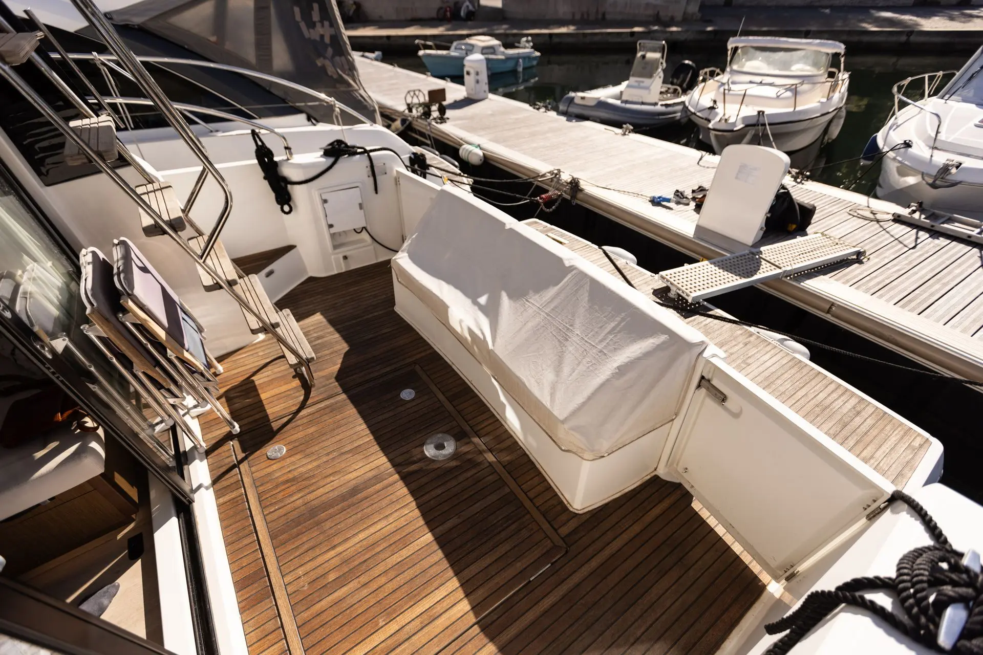 Jeanneau Merry Fisher 38 Fly — Vue du cockpit arrière d’un bateau amarré, avec banquette et plancher en teck.