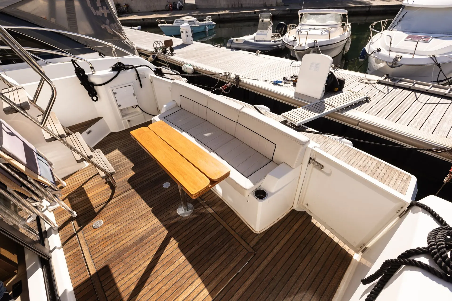 Jeanneau Merry Fisher 38 Fly — Cockpit arrière avec banquette en U, table en teck et pontons environnants.