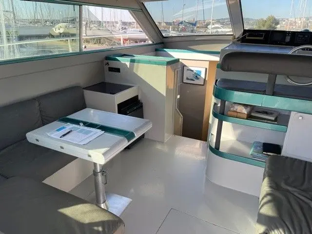 Ferretti Altura 36 — Vue intérieure du poste de pilotage et du carré, avec vue sur une marina.