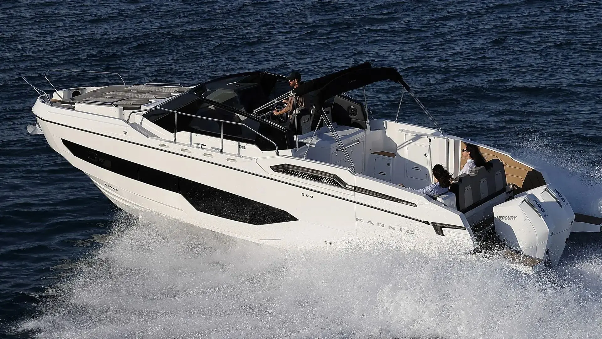 Karnic CS10 — Bateau à moteur blanc vu de trois quarts en navigation, avec trois personnes à bord.