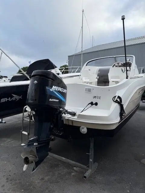 Quicksilver 620 CRUISER — Vue arrière trois-quarts d’un bateau blanc à moteur hors-bord sur remorque.