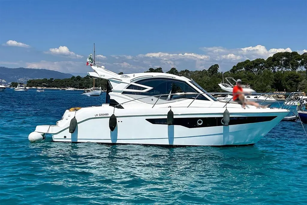 Galeon 310 Htc — Bateau à moteur blanc vu de profil sur une mer calme, avec une personne à bord.
