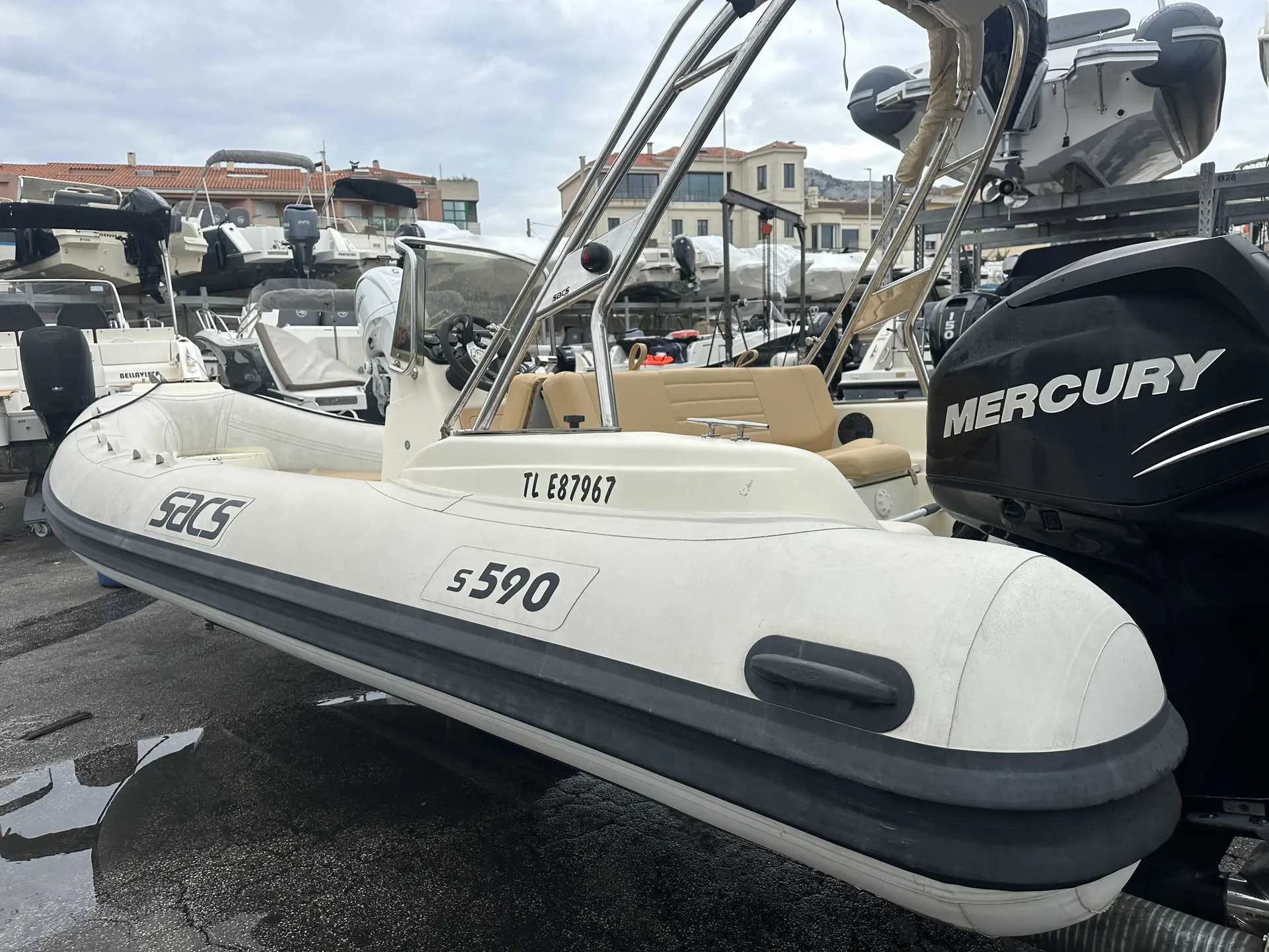 Sacs S 590 — Bateau semi-rigide blanc vu de trois quarts dans un port, avec moteur hors-bord.
