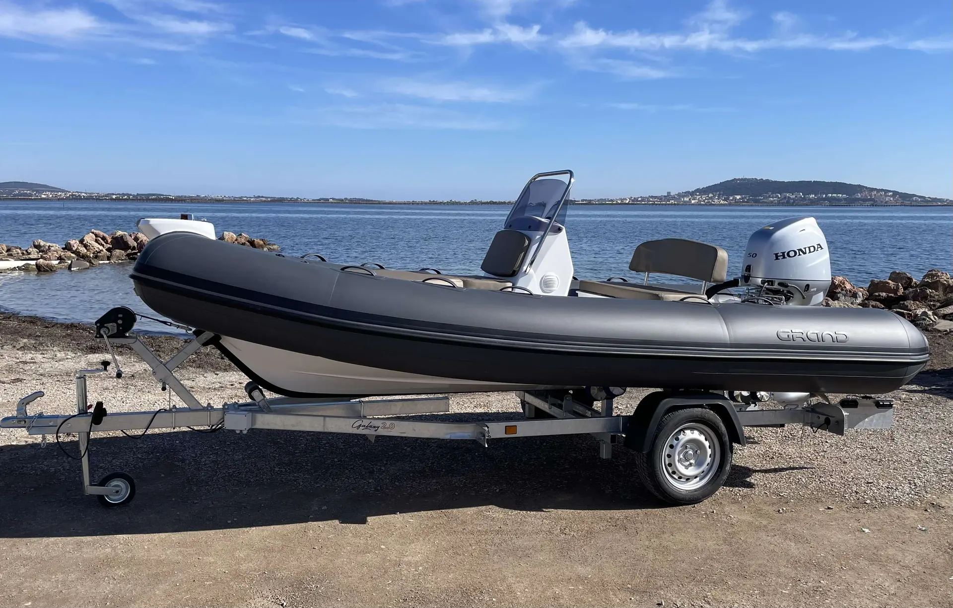 Grand Silver Line S 470 Nl — Bateau pneumatique gris posé sur sa remorque au bord de l’eau.