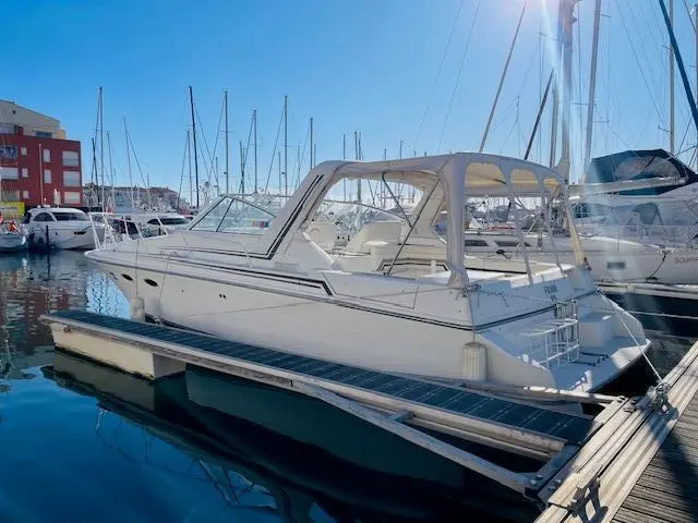 Trojan Fuchur — Bateau à moteur blanc amarré dans une marina, vu de trois quarts.