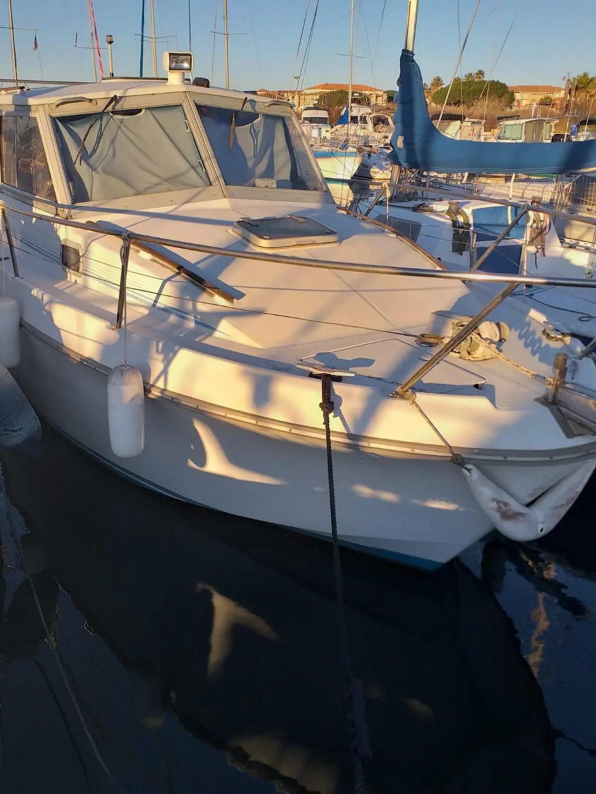Beneteau Antares 730 — Vue rapprochée de l'avant et du rouf d'un voilier amarré dans un port.