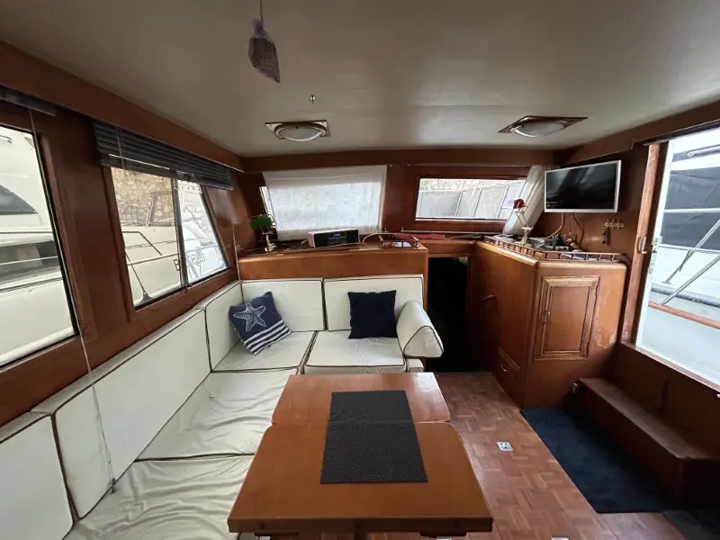 Ocean Alexander 38 — Salon intérieur avec banquette, table, poste de pilotage et rangements en bois.