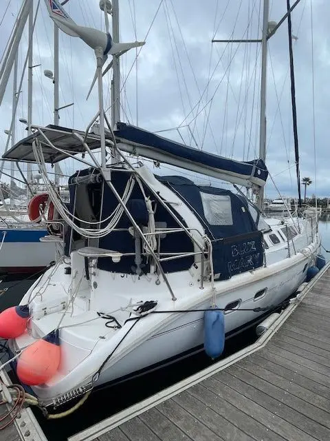 Hunter 410 — Voilier blanc et bleu amarré à un ponton, vu de trois quarts arrière.