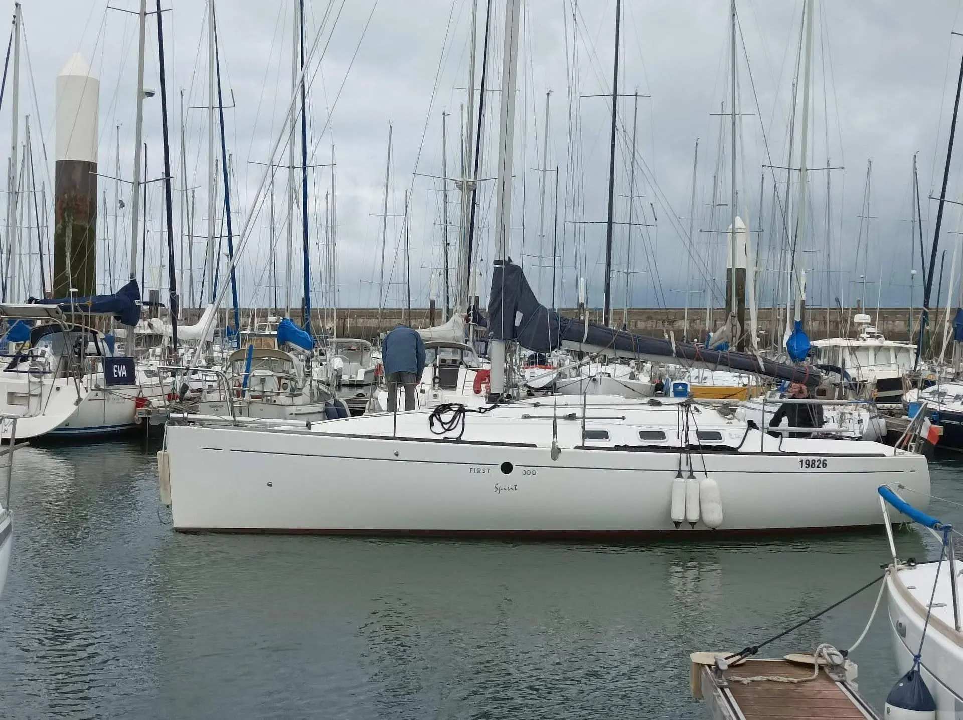Beneteau First 300 Spirit — Voilier blanc vu de profil, amarré dans un port parmi d'autres bateaux.