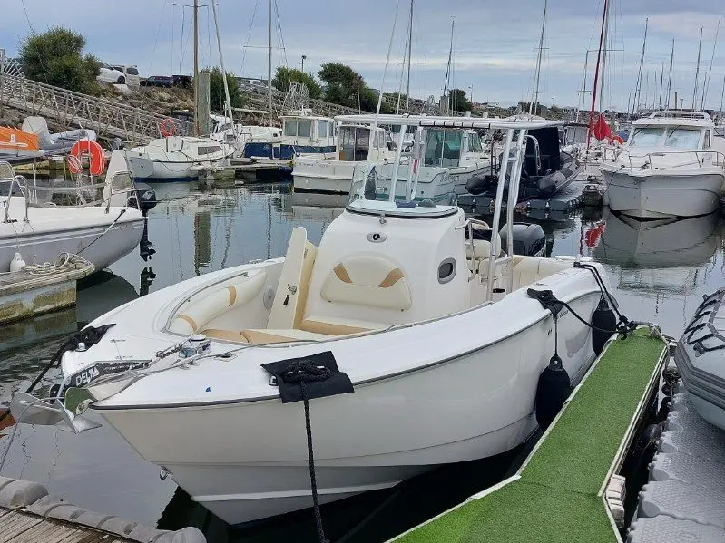 Boston Whaler 240 Outrage — Bateau blanc amarré dans une marina, photographié de trois quarts avant.
