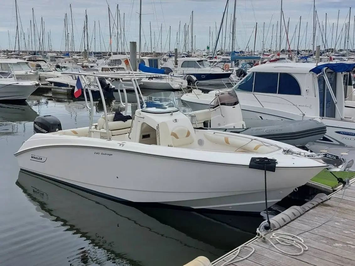 Boston Whaler 240 Outrage — Bateau blanc amarré dans une marina, photographié de trois quarts avant.
