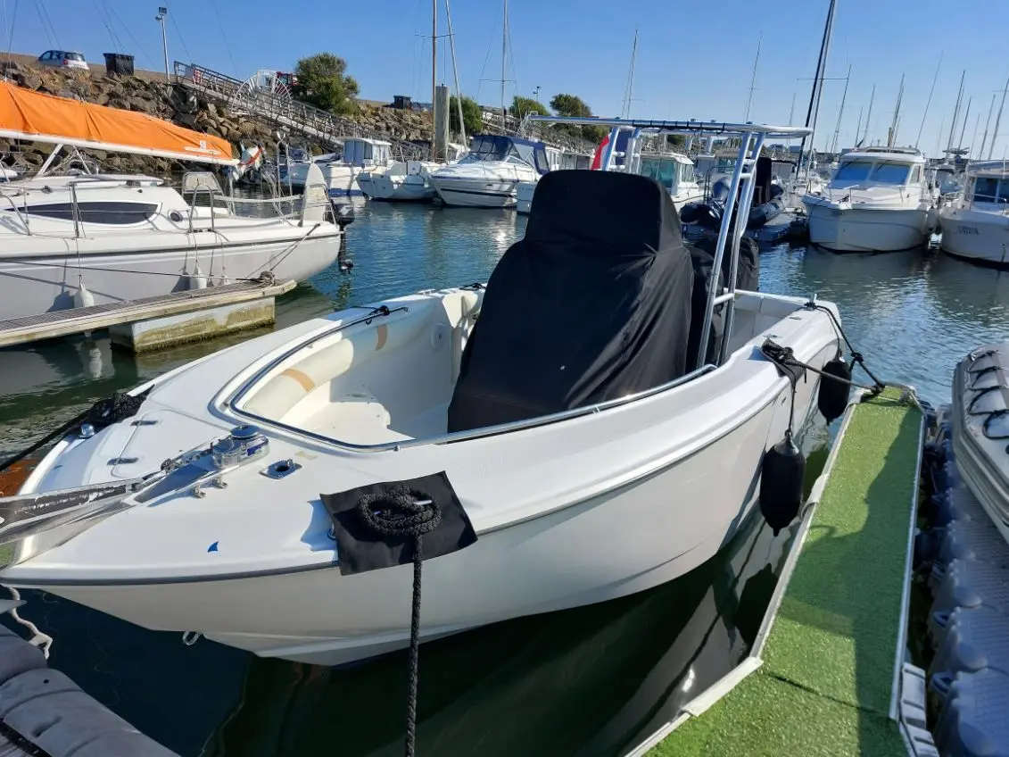Boston Whaler 240 Outrage — Bateau blanc amarré dans un port de plaisance, vu de trois quarts avant.