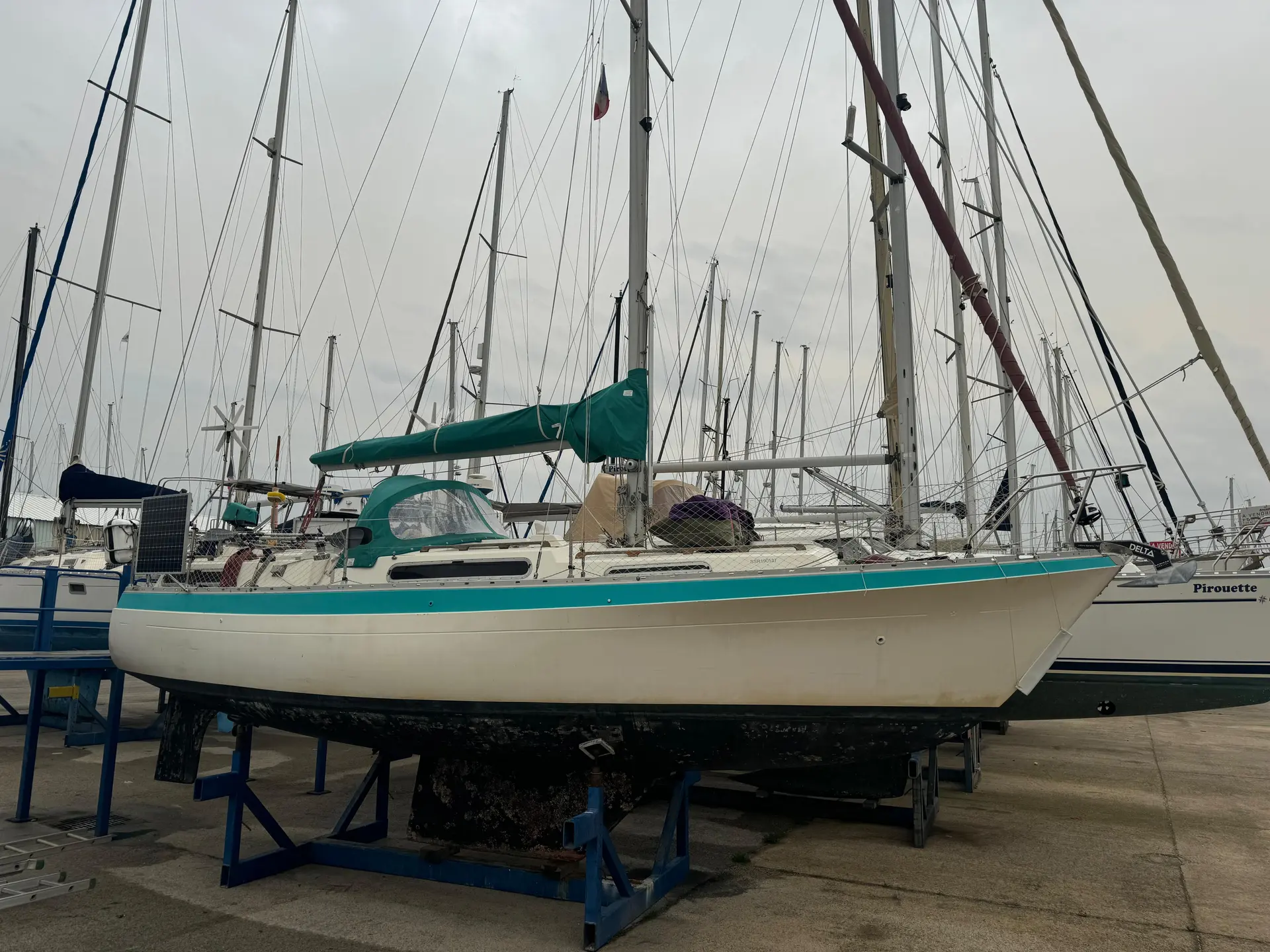 Moody 33 — Voilier vu de profil, posé sur bers dans une marina, entouré d'autres bateaux.