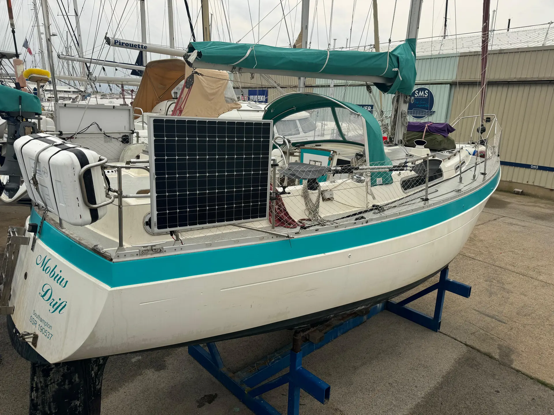 Moody 33 — Voilier blanc et turquoise présenté à terre, vu depuis l’arrière tribord.