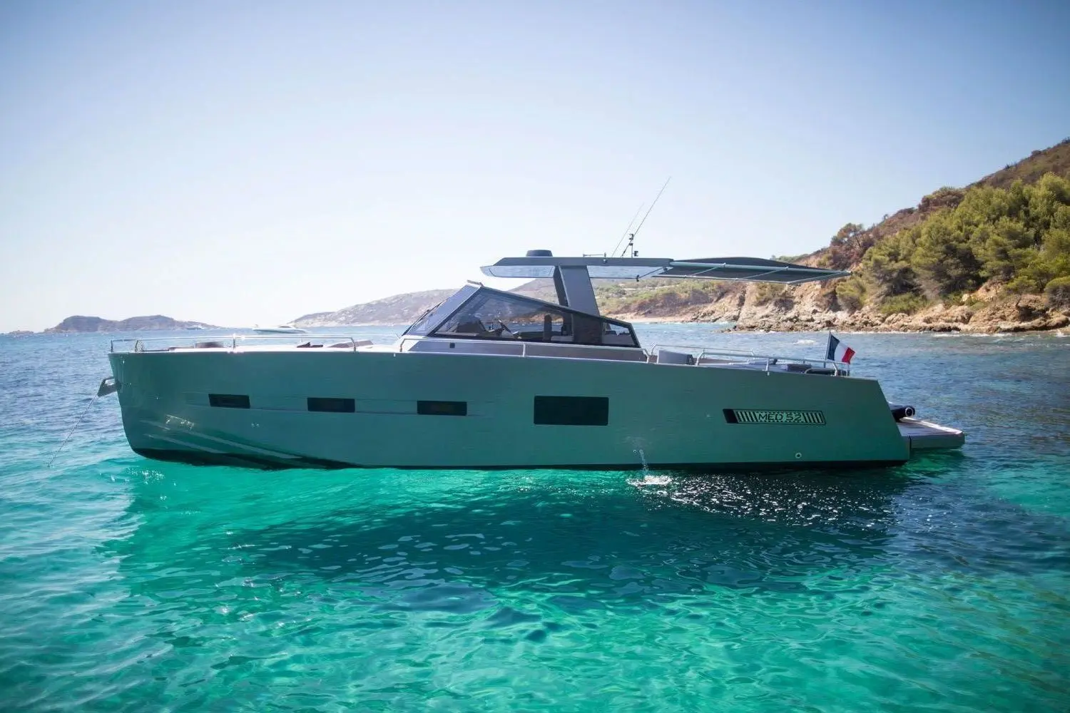 Medyacht MED 52 — Bateau à moteur vu de profil dans une baie aux eaux turquoise.
