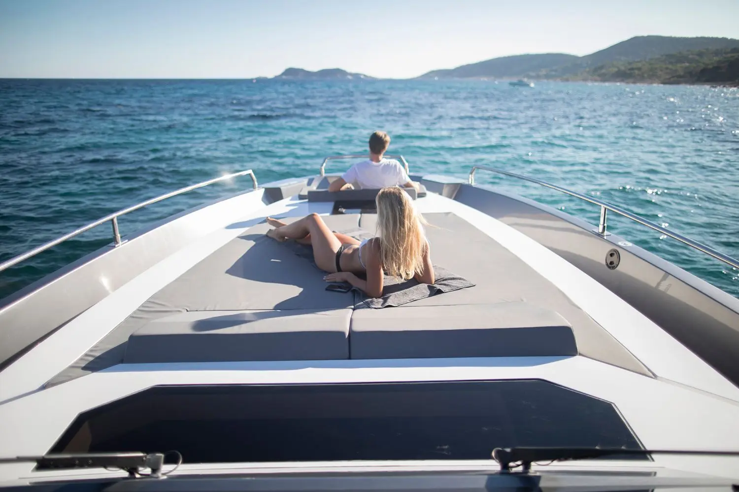 Medyacht MED 52 — Vue de l’avant d’un bateau naviguant en mer, avec deux personnes sur le bain de soleil.