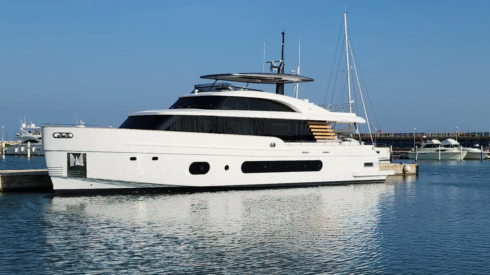 Azimut Magellano 25 — Vue latérale d’un yacht blanc amarré dans une marina, au soleil.