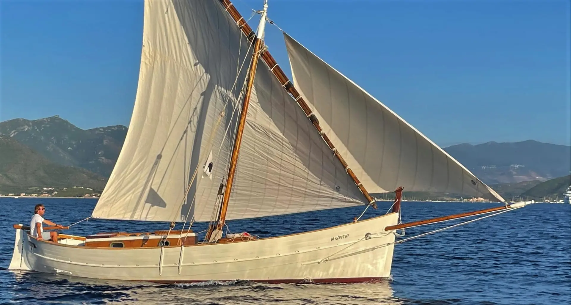 Cantiere Sangermani Rivaneto Ligure — Voilier traditionnel sous voiles, photographié de profil sur une mer calme.