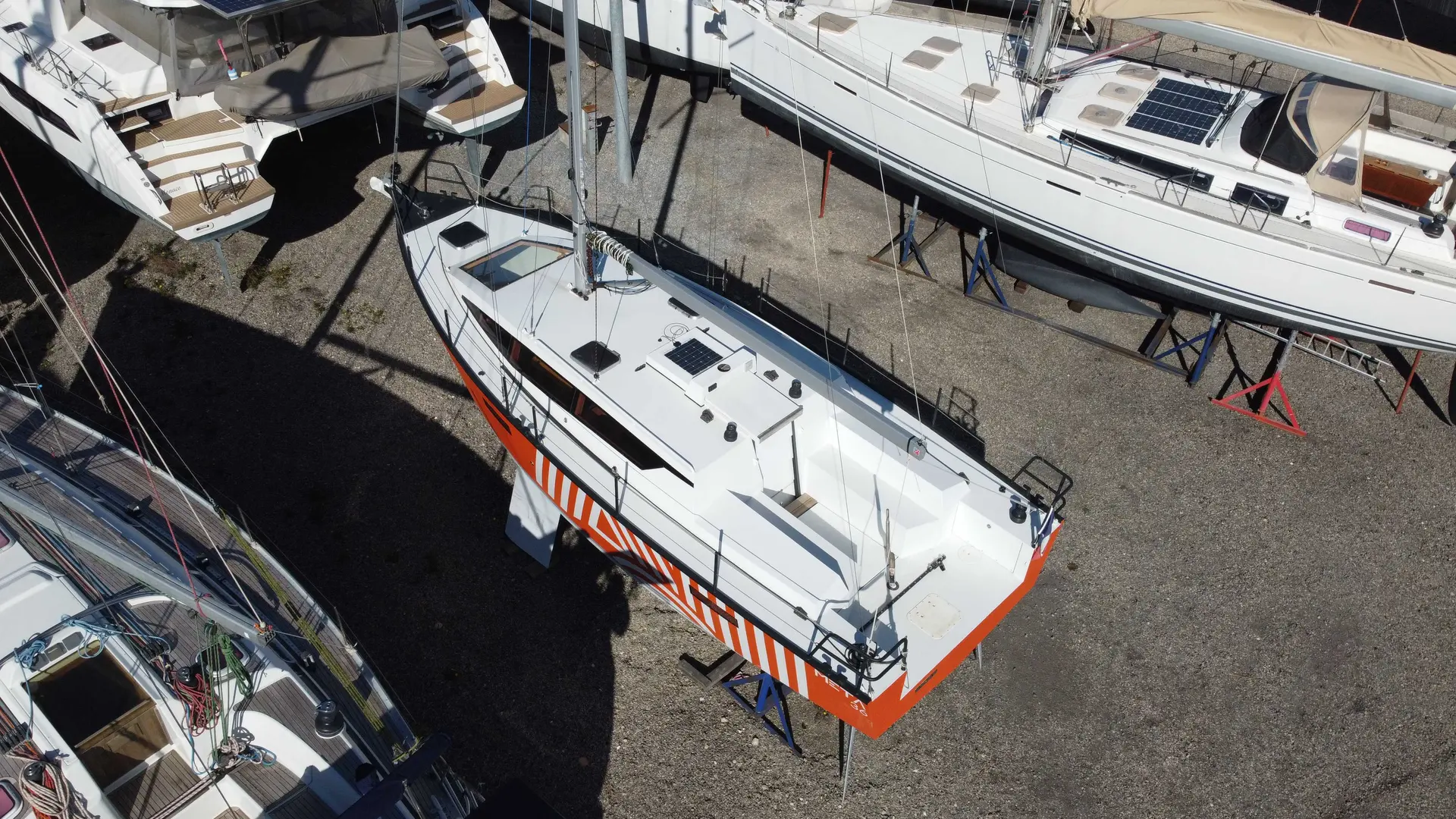 Meta 36 — Vue aérienne d’un voilier blanc et orange sur bers dans un chantier naval.