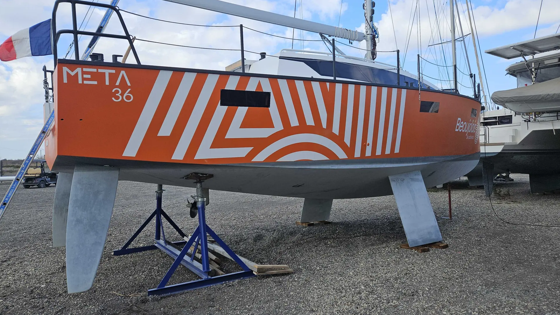 Meta 36 — Voilier orange sur bers, photographié de profil dans un chantier naval.