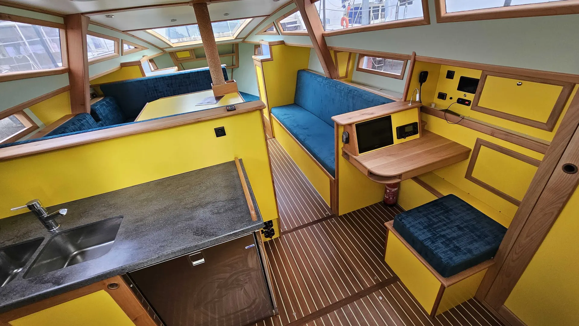 Meta 36 — Vue intérieure d’un bateau montrant une cuisine et un carré avec banquettes bleues.