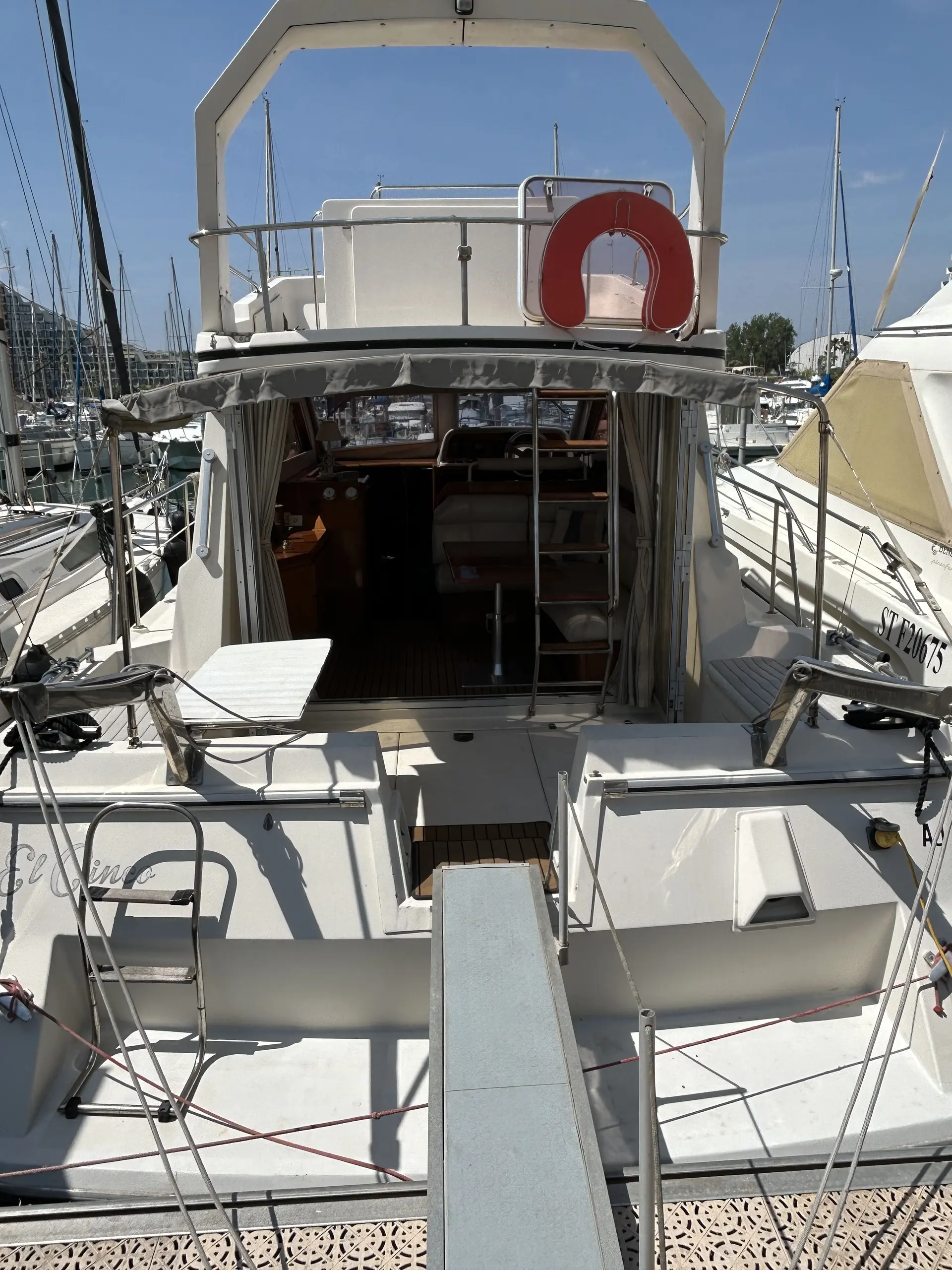 Arcoa 1077 — Vue arrière d’un bateau à moteur amarré dans une marina.