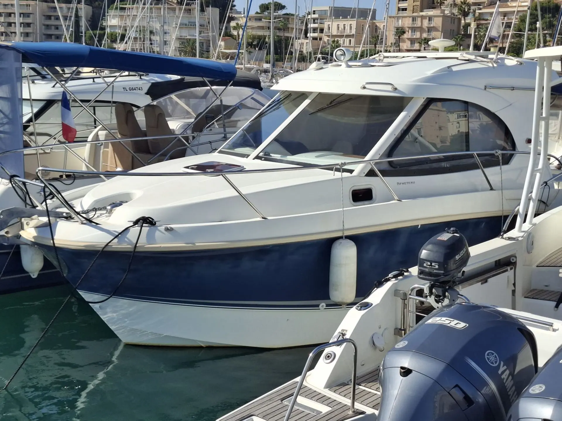 Beneteau antares 8s — Bateau à moteur blanc et bleu amarré dans un port, vu de trois quarts.
