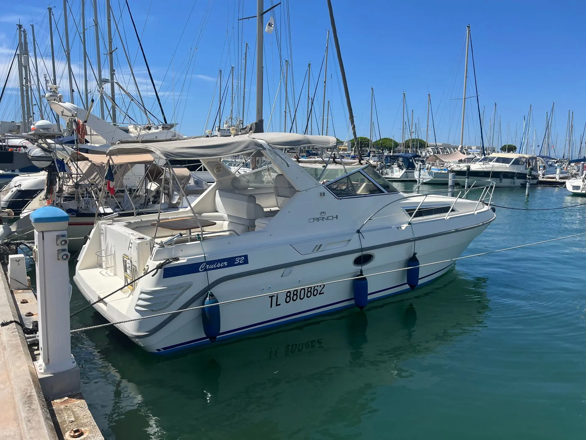 Cranchi Cruiser 32 — Bateau à moteur blanc amarré dans une marina, vu de trois quarts.