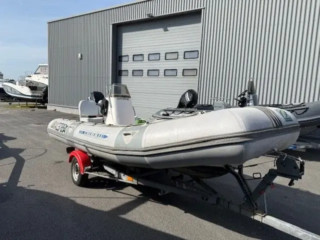 Zodiac Cherokee 495 — Bateau pneumatique gris et blanc sur remorque, devant un hangar.