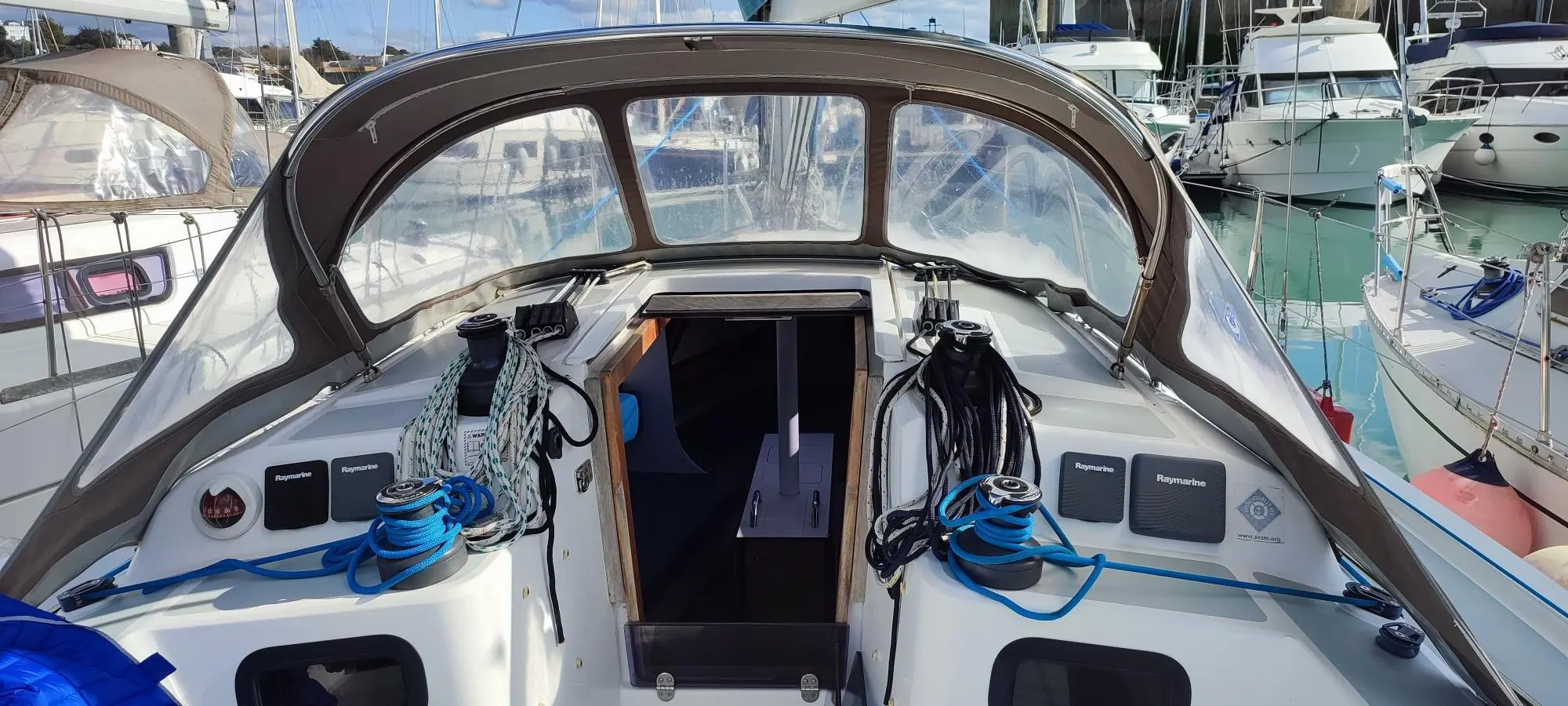 RM Yachts RM 890 — Vue du cockpit arrière d’un voilier amarré, avec capote, winchs et cordages.