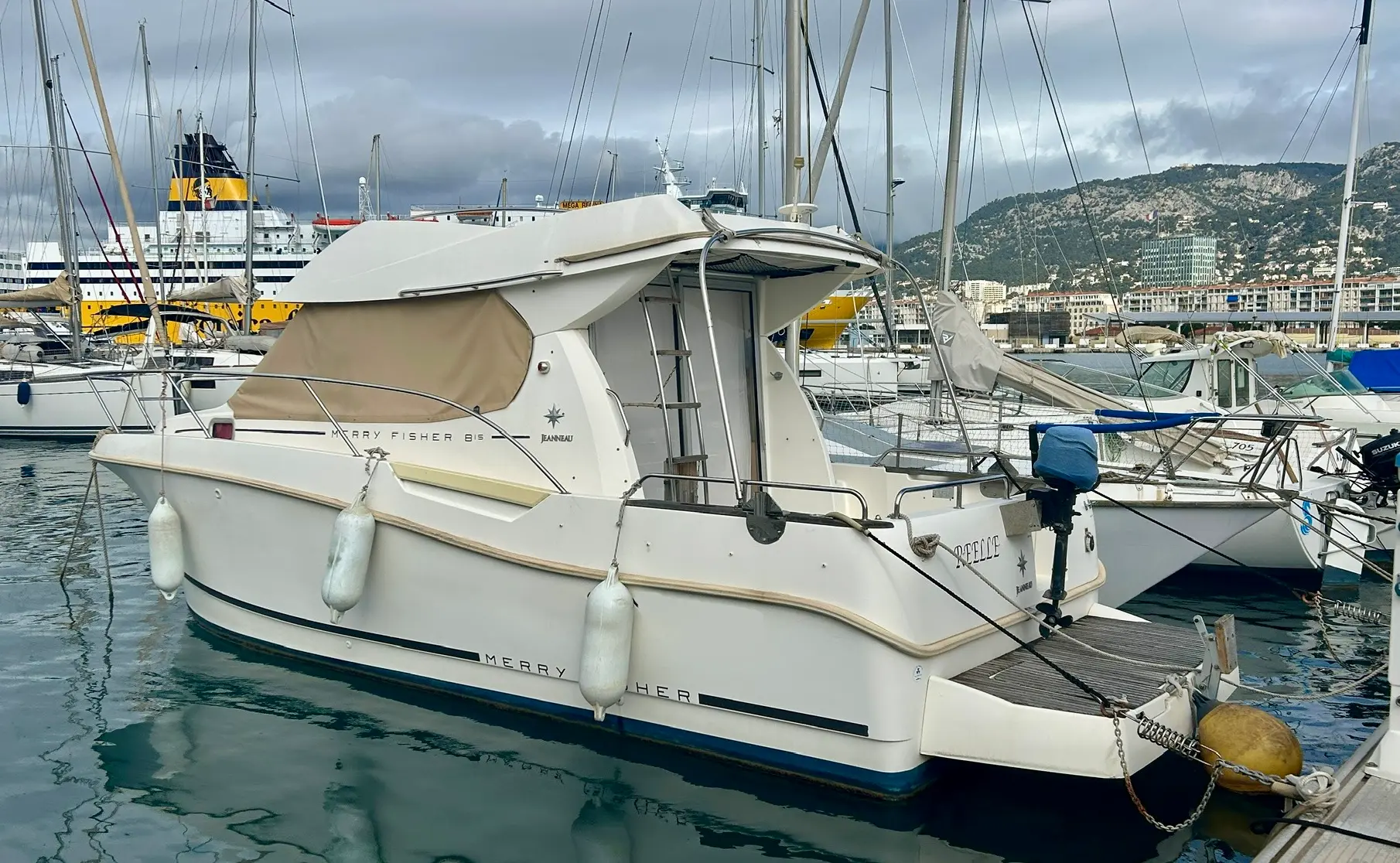 Jeanneau Merry Fisher 815 — Bateau à moteur blanc amarré dans un port, vu de trois quarts arrière.