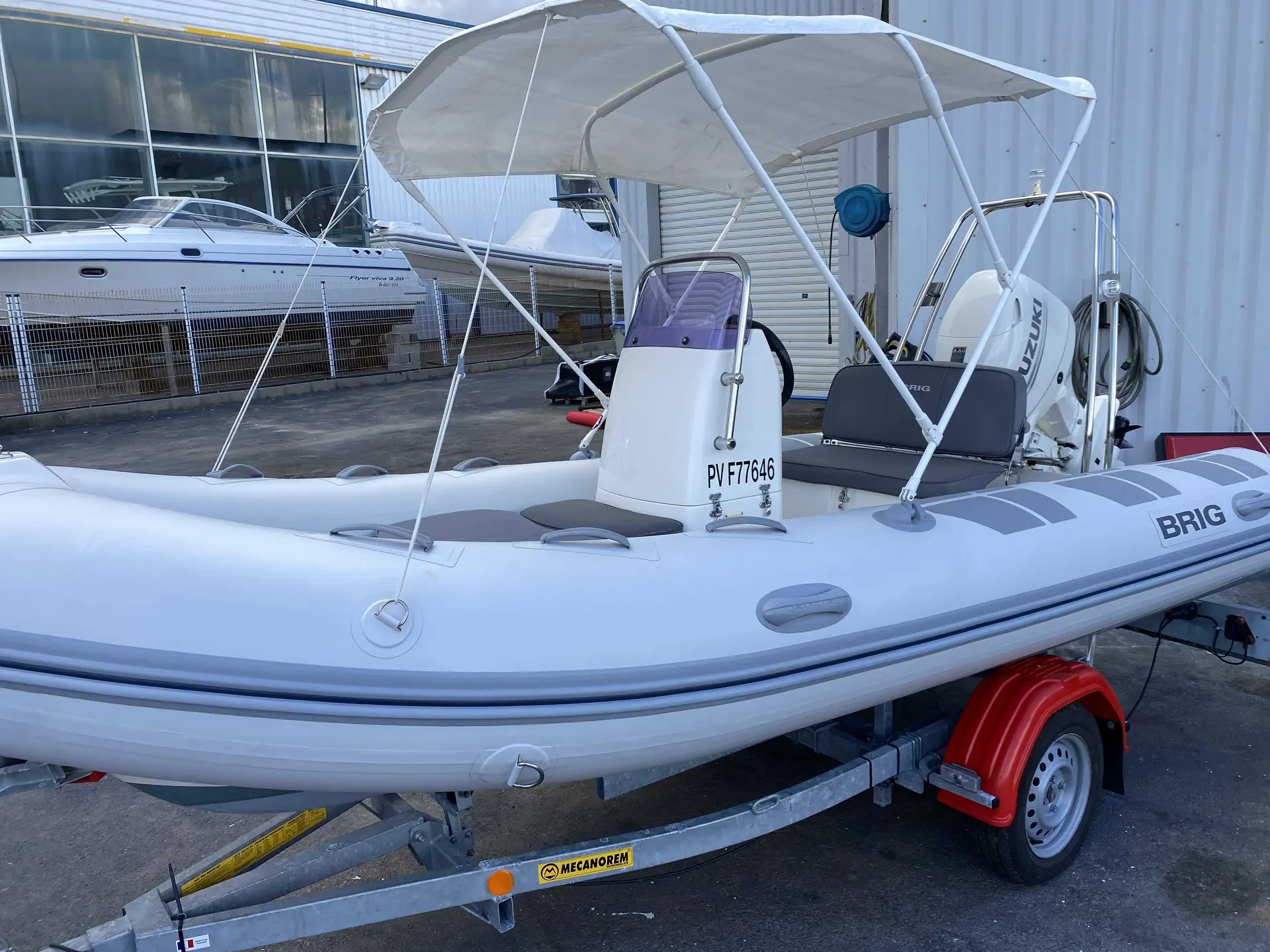 Brig Falcon 450 — Bateau pneumatique blanc avec console centrale, moteur hors-bord et taud sur remorque.