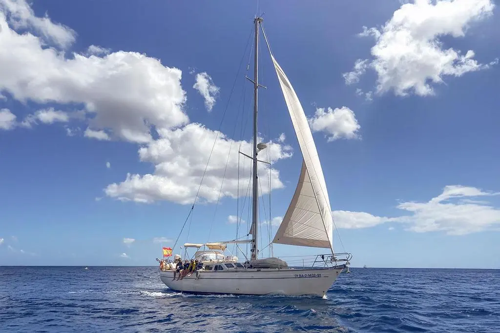 North Wind 47 — Voilier vu de profil en mer, toutes voiles hissées sous un ciel nuageux.