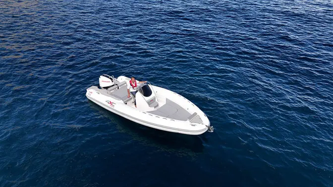 4XC HA23 — Vue aérienne d’un bateau blanc à moteur sur une mer bleue.