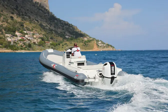 4XC HA27 — Un bateau semi-rigide navigue près d’une côte rocheuse, laissant un sillage marqué.