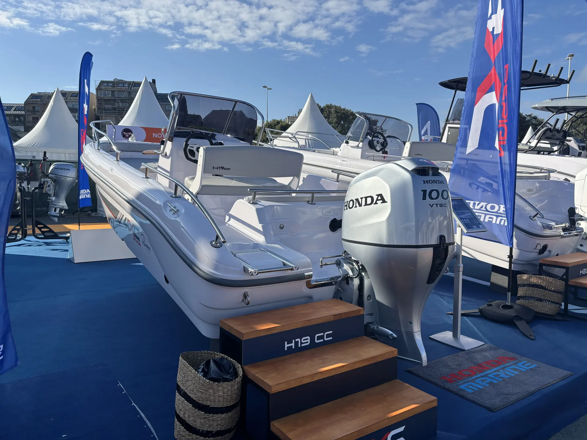 4XC H19CC — Bateau semi-rigide blanc exposé sur un stand nautique, vu de l’arrière.
