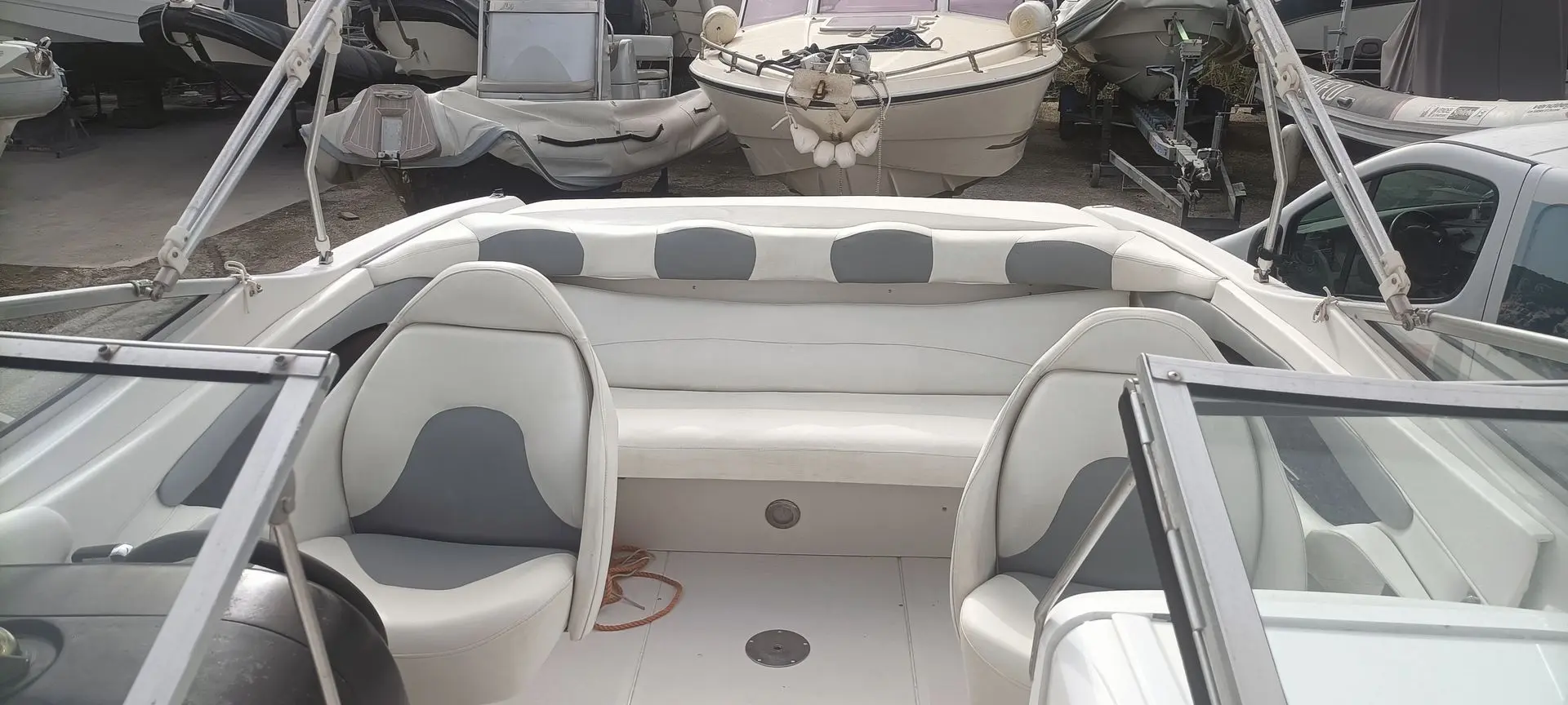 Four Winns Horizon 240 — Vue du cockpit avec banquette arrière, sièges avant et pare-brise.