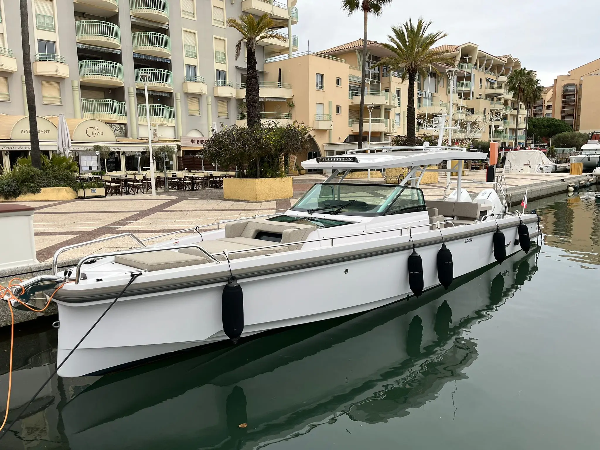 Axopar 37 Suntop — Bateau à moteur blanc amarré dans un port, vu de trois quarts.