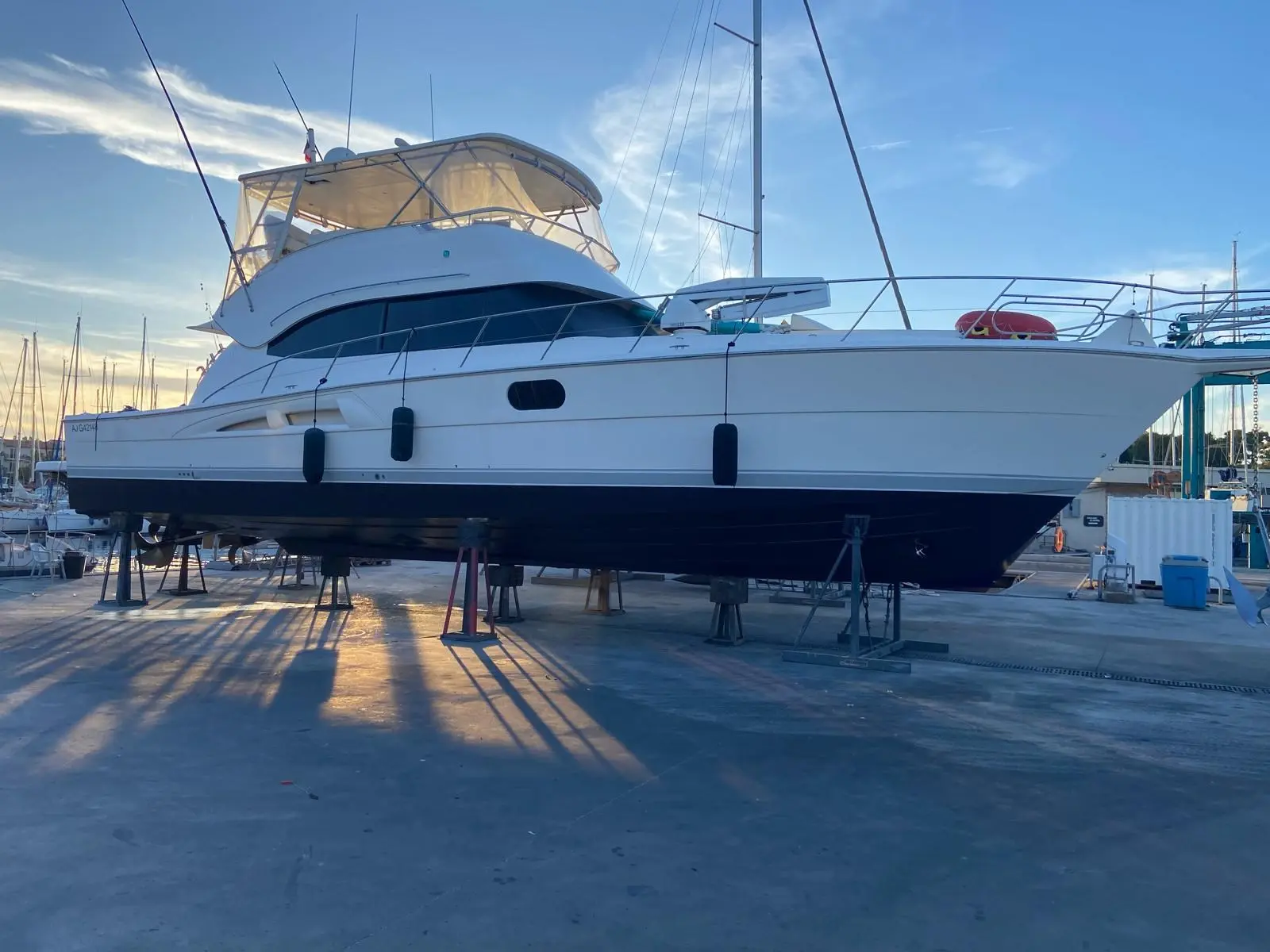 Riviera 58 Open Flybridge — Vue latérale d’un bateau blanc à moteur sur bers dans un chantier naval.