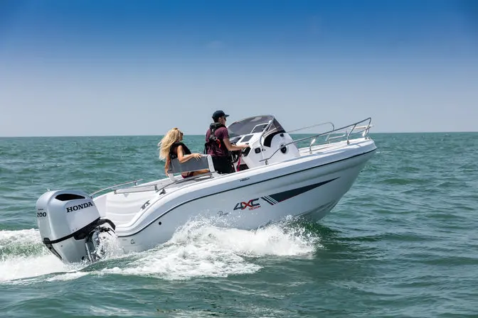 4XC H26SD — Bateau à moteur blanc naviguant sur une mer agitée avec deux personnes à bord.